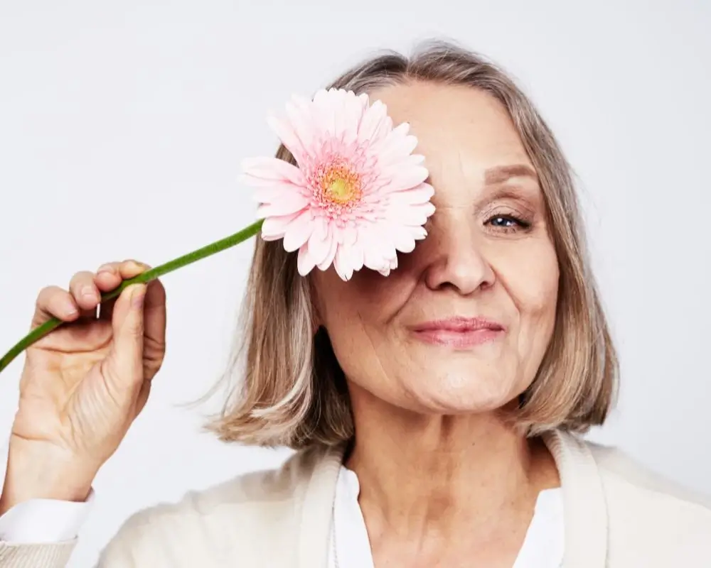 Starsza kobieta z kwiatem przy oku